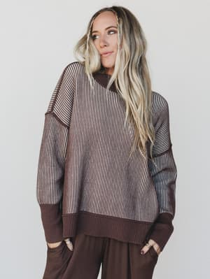 Woman wearing a brown and beige striped sweater with a plain background