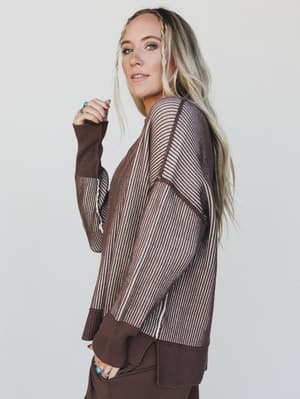 Woman wearing a brown and beige striped sweater against a plain background