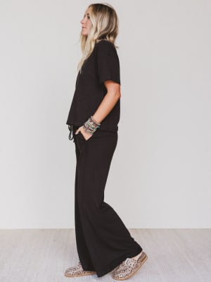 Person wearing a black outfit with wide-leg pants against a white background