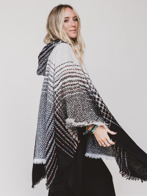 Woman wearing a patterned poncho against a plain background