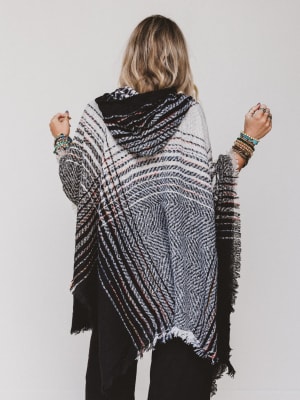 Person wearing a patterned poncho against a plain background
