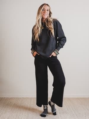 Woman wearing a black sweater and pants with a plain background