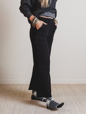 Person wearing black pants and a dark sweater with a plain background