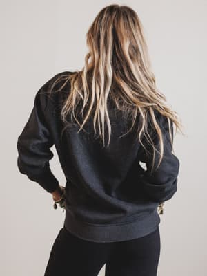 Person wearing a black bomber jacket with a neutral background