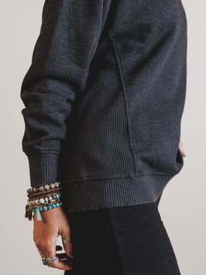 Person wearing a dark gray sweater with a plain background