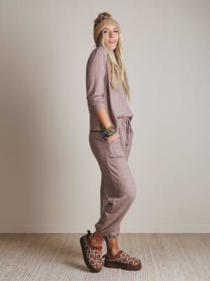 Woman wearing a matching pink outfit with a beanie and sandals in a neutral setting