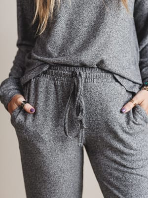 Woman wearing a gray sweatshirt and sweatpants set with a neutral background