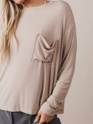 Beige long-sleeve top with a pocket on a plain background