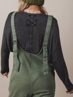 Person wearing green overalls with a plain background