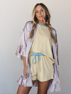 A relaxed, dreamy layered look featuring a flowy daisy-print kimono robe over a yellow striped matching set — the kind of outfit that makes staying in feel like a whole vibe.