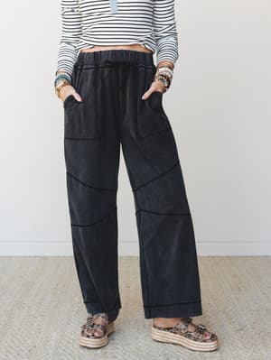 Wide-leg pants in a washed ash black with curved patchwork seam detailing, styled with a striped long-sleeve top, stacked bead bracelets, and platform espadrille sandals — easy and a little unexpected.
