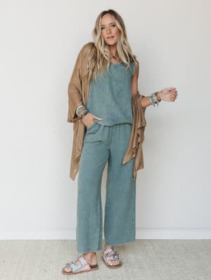A relaxed, earthy outfit pairing — a dusty sage matching tank and wide-leg pant set layered under a camel open-front cardigan, styled with stacked beaded bracelets and embellished sandals for that effortlessly collected, everyday boho feel.