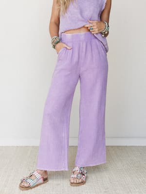 Lavender wide-leg gauze pants styled as a matching set with a coordinating top, accessorized with stacked boho bracelets and beaded sandals — relaxed, sunny, and effortlessly put-together.