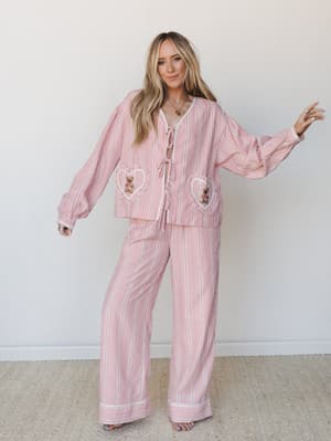 A whimsical matching set in pink plaid with heart-shaped pockets featuring tiny teddy bear patches — the kind of outfit that makes a Sunday morning feel like a whole personality.