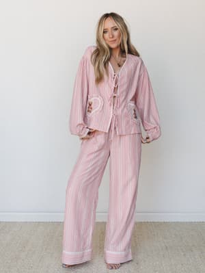 A matching pink gingham two-piece set with whimsical heart-shaped ruffle pockets and lace-up front detailing — the kind of outfit that blurs the line between cozy-at-home and going-somewhere-cute.