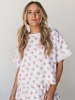 A flowy floral-print top with flutter sleeves and scallop lace trim, worn as a matching set with a coordinating tiered skirt — soft, romantic, and the kind of thing you'd reach for on a slow Saturday morning.