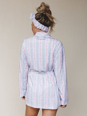 Shot from the back, a model in a floral-striped robe and matching scrunchie headband gives off total slow-morning energy — the kind where you're making coffee and it still feels like a whole look.