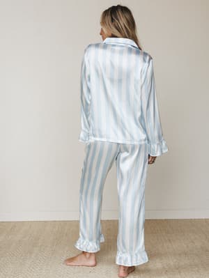A satin stripe pajama set shot from the back — the kind of set that makes a slow morning feel like a whole personality.