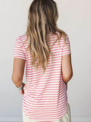 A back-view shot of a relaxed striped tee in coral and white, styled with light bottoms and stacked bracelets — the kind of easy top that makes a Tuesday feel like a beach town errand run.