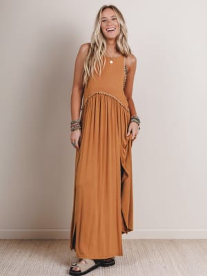 Woman wearing a long brown dress against a plain background