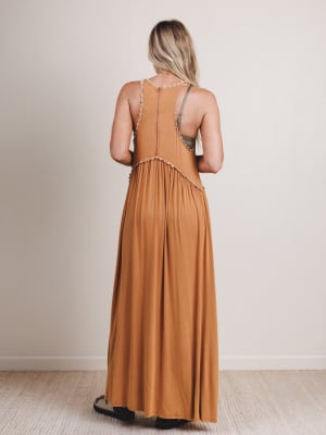 Woman wearing a long mustard yellow dress against a plain background