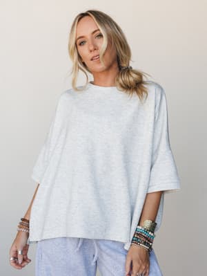 An oversized heather gray sweatshirt tee styled with matching drawstring pants and stacked boho bracelets — the kind of effortless, cozy-cool look that feels intentional without trying.
