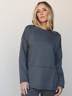 A relaxed, oversized long-sleeve sweatshirt top in heathered charcoal, styled with matching pants and stacked silver rings — the kind of set that looks like you tried just enough.