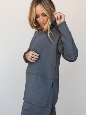 A relaxed-fit charcoal sweatshirt tunic styled with matching pants and layered silver and turquoise jewelry — the kind of set that looks intentional without trying too hard.