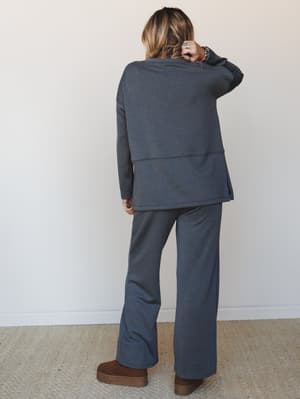 Shot from the back, this matching charcoal set pairs an oversized long-sleeve top with wide-leg flare pants — the kind of cozy-collected outfit that feels like staying in but looks like going out.