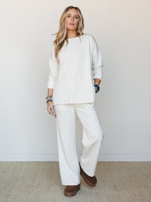 A cream matching sweatshirt-and-wide-leg-pant set styled with stacked beaded bracelets and chocolate platform clogs — the kind of outfit that looks intentional but feels like staying in.