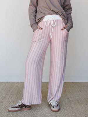Wide-leg striped lounge pants in dusty pink and cream styled with a tucked taupe long-sleeve and leopard print sneakers — the kind of outfit that somehow looks intentional at 9am on a Saturday.