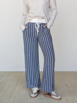 Wide-leg navy striped lounge pants styled with a relaxed cream long-sleeve top and leopard-print sneakers — the kind of outfit that looks like you tried just enough.