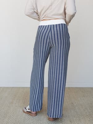 A back-view shot of wide-leg pants in a navy and cream grid stripe knit, paired with a slouchy blush top and leopard sandals — relaxed and put-together in equal measure.