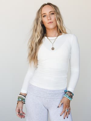 A ribbed white long sleeve top styled with light grey pants and stacked turquoise and stone bracelets — the kind of effortless base layer that makes everything else look intentional.