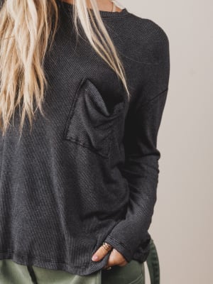 Person wearing a dark gray long-sleeve shirt against a neutral background