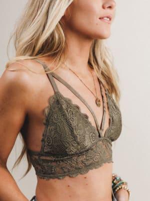 Woman wearing an olive lace bralette against a neutral background