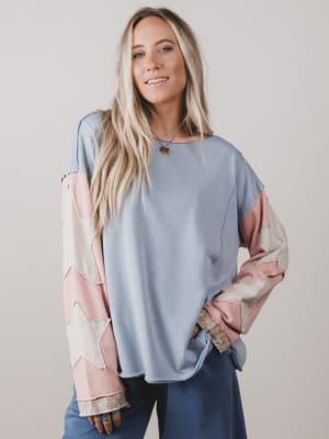 Woman wearing a light blue and pink patterned top against a plain background