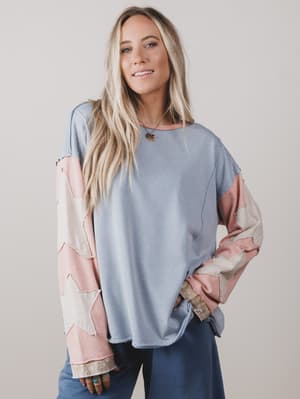Woman wearing a light blue and pink patterned top against a plain background