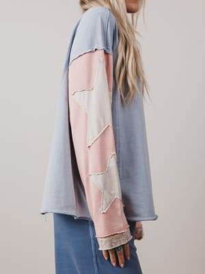 Person wearing a long-sleeve shirt with a patchwork design on a plain background