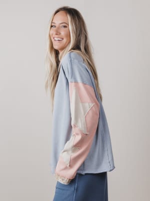 Woman wearing a light blue shirt with pink sleeves against a plain background