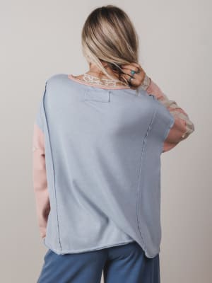 Woman wearing a light blue sleeveless top and blue pants against a plain background