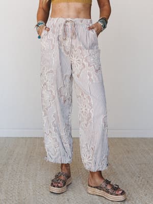 Wide-leg striped pants with floral embroidery overlay styled with a cropped knit top and espadrille platform sandals — relaxed and expressive, the kind of pants that feel as good as they look.