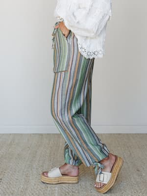 A side-profile shot of multicolor striped wide-leg pants paired with a white eyelet lace top and cream platform espadrille sandals — relaxed, earthy, and effortlessly put-together.