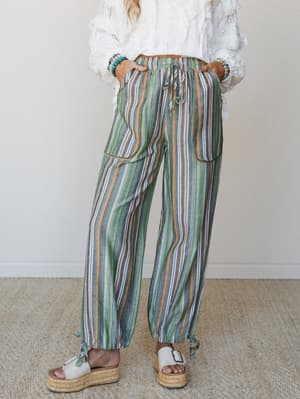 Relaxed multicolor stripe wide-leg pants with a drawstring waist and patch pockets, styled with a white lace ruffle top and platform espadrilles for an easy boho-travel feel.