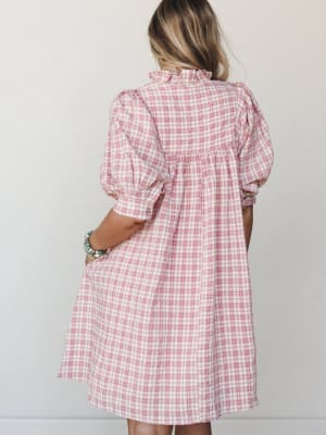 A back view of a pink plaid midi dress with puff sleeves and a ruffle neckline — the kind of dress that makes you want to go somewhere worth getting dressed for.