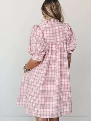 A back view of a pink plaid midi dress with puff sleeves and a ruffle neckline — the kind of dress that makes you want to go somewhere worth getting dressed for.