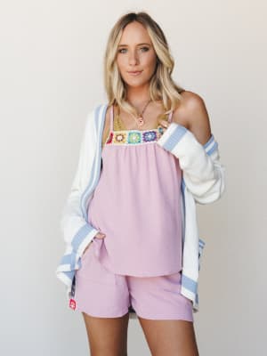 A breezy summer look layered with intention — a lilac cami top with a colorful granny square crochet panel paired with matching lilac shorts, topped with an oversized cream cardigan with periwinkle stripe trim.