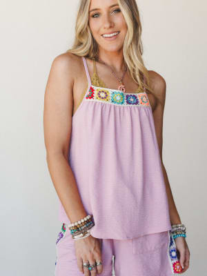 A flowy lilac cami top with a colorful granny square crochet panel at the bust, styled with matching wide-leg pants and layered boho jewelry for a playful, sun-drenched summer feel.