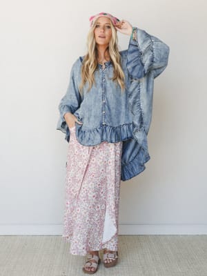 An oversized acid-wash denim ruffle top layered over a flowy floral maxi skirt in dusty rose — the kind of outfit that looks like it came together effortlessly but definitely did not.