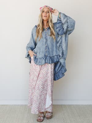 An oversized acid-wash denim ruffle top layered over a flowy floral maxi skirt in dusty rose — the kind of outfit that looks like it came together effortlessly but definitely did not.